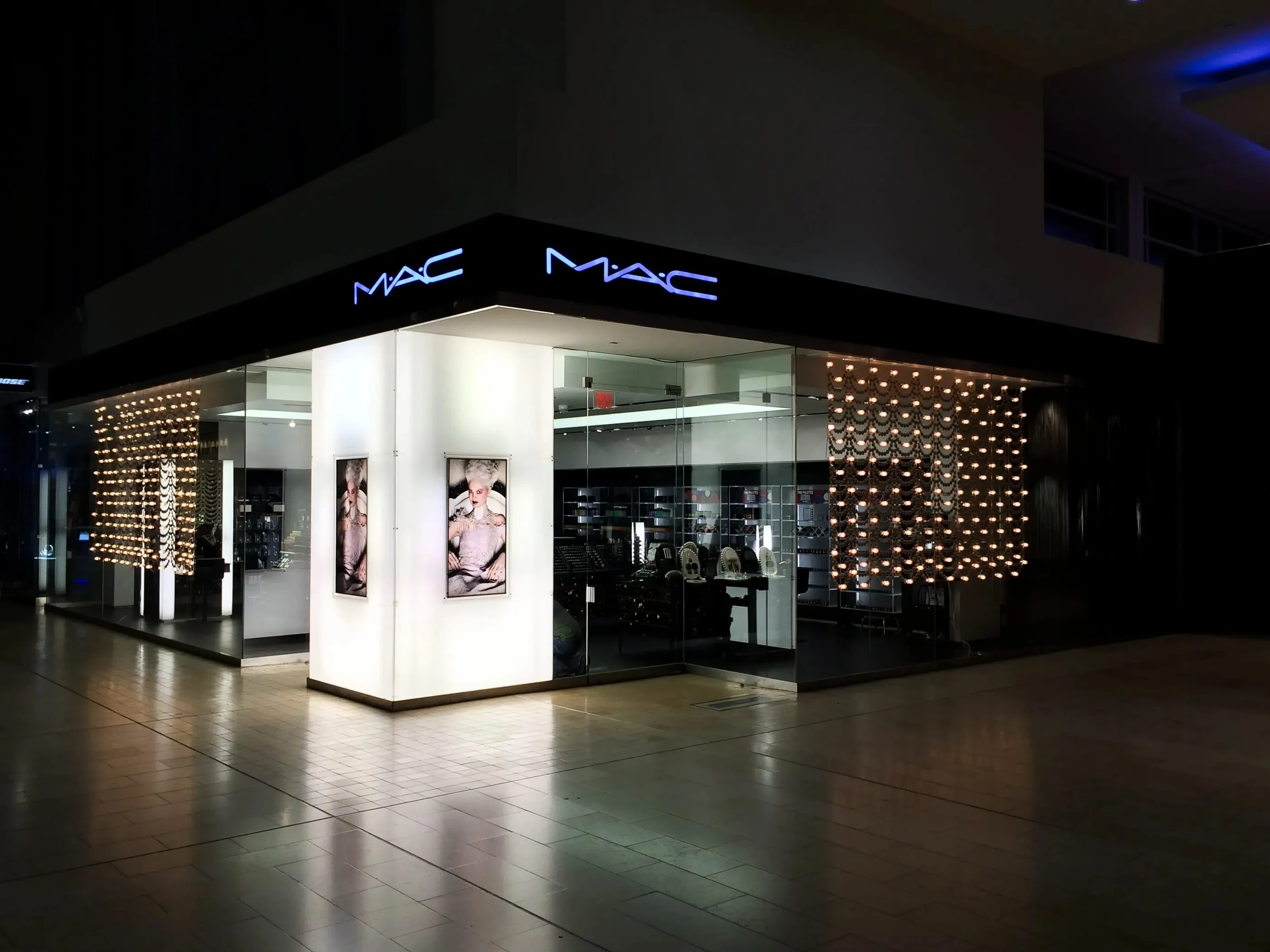 M·A·C corner storefront with backlit graphics in a mall at night