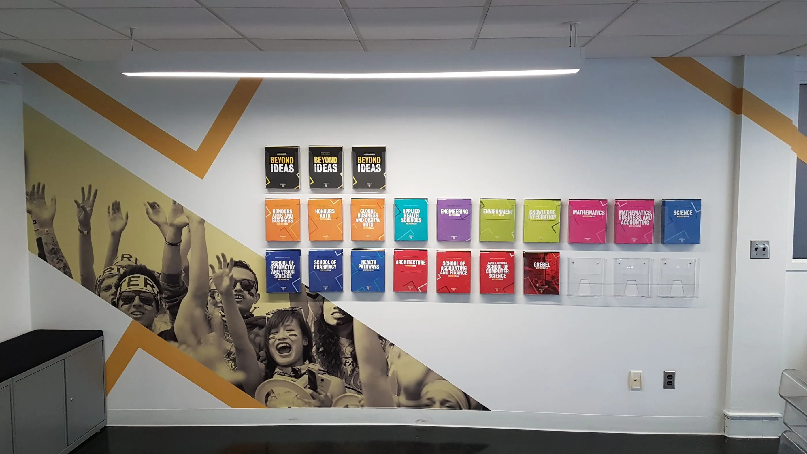 Office wall graphic with angled yellow bands, a photo mural and a grid of coloured panels